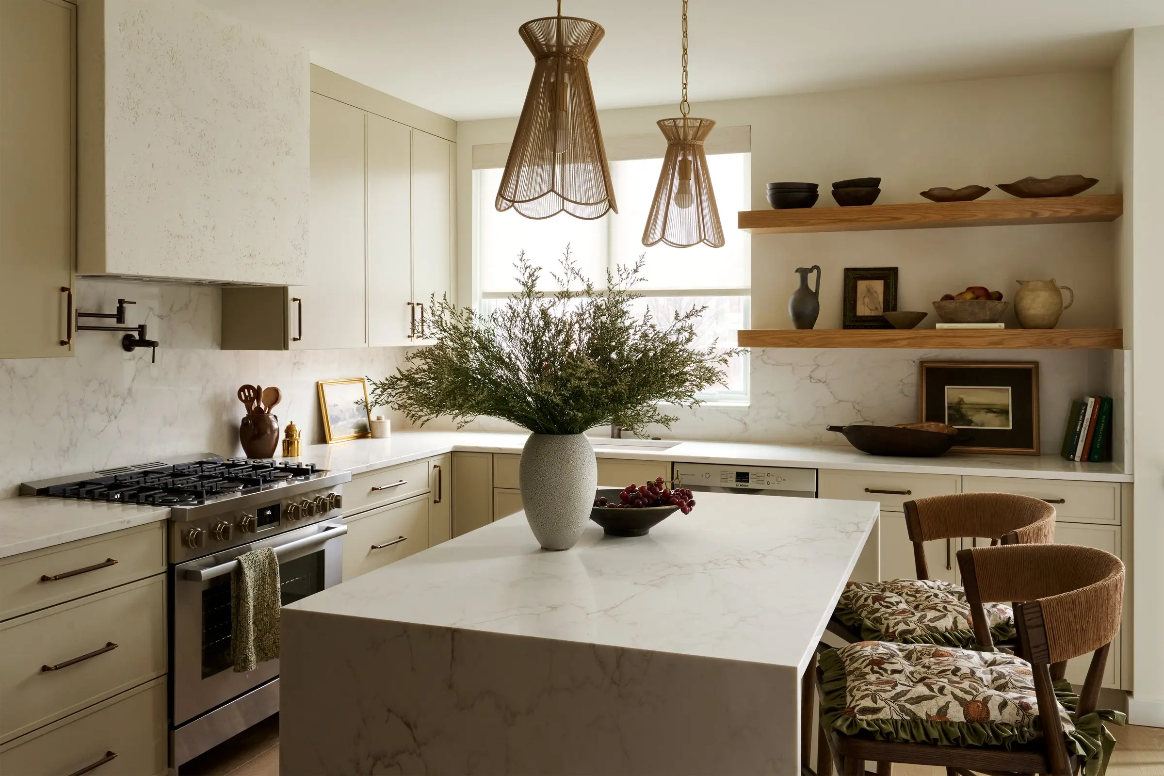 Kitchen with a waterfall marble island, plaster range hood, open wood shelving and woven pendant lights