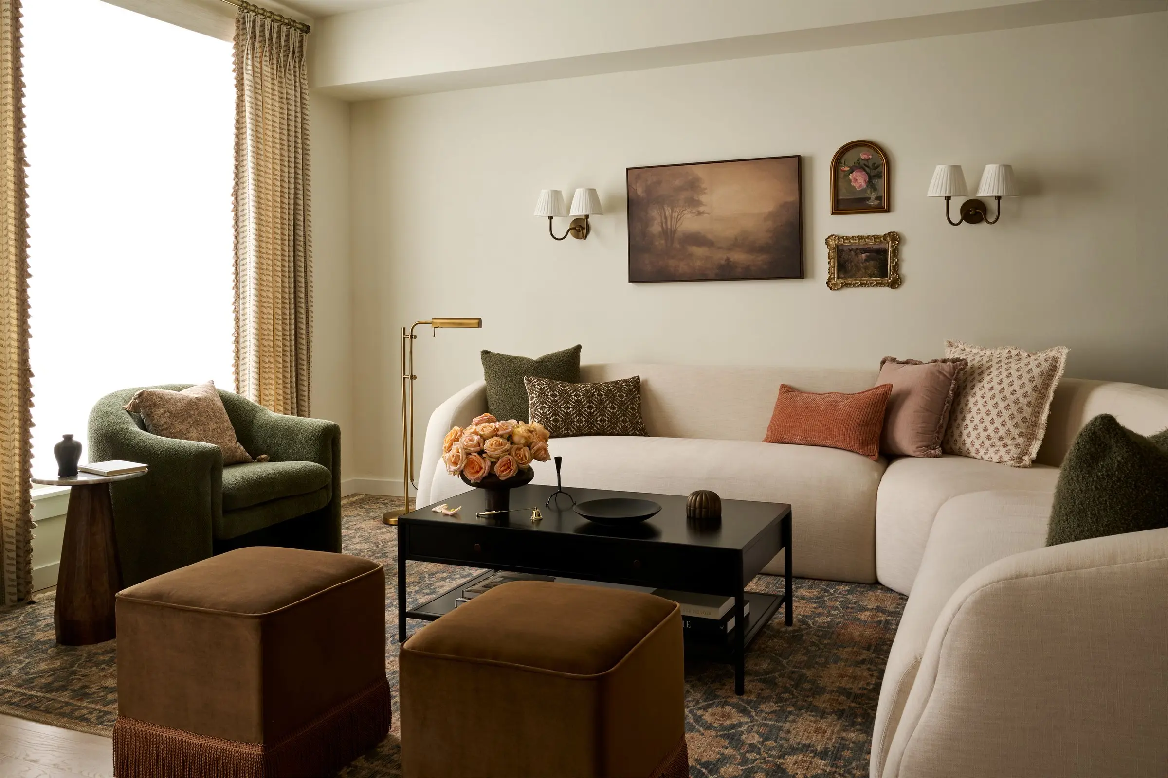 Center City Philadelphia townhome living room with a curved cream sofa, olive boucle armchair and landscape paintings, designed by Toile & Oak