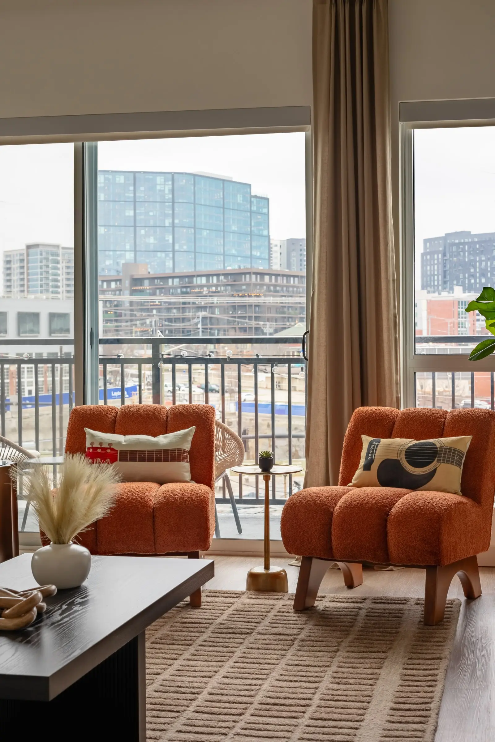 Pair of burnt orange boucle chairs facing floor-to-ceiling windows and the city