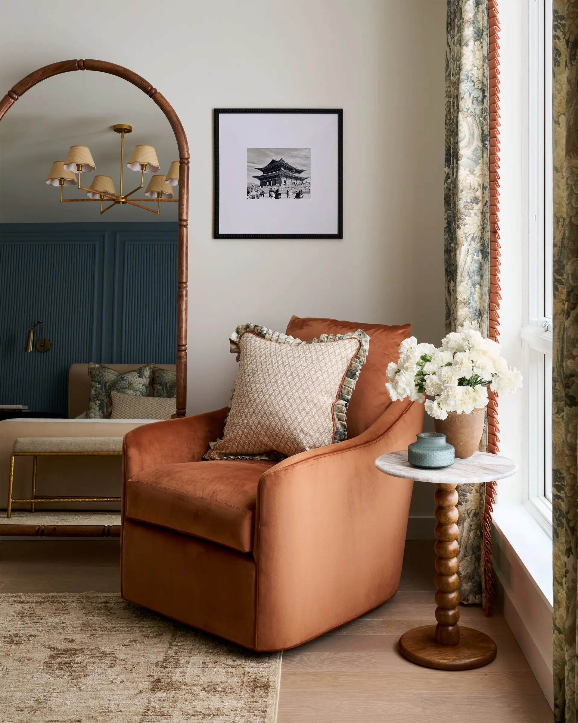Rust velvet swivel chair, a marble side table and white hydrangeas in a sunlit corner of the Wendle Bedroom