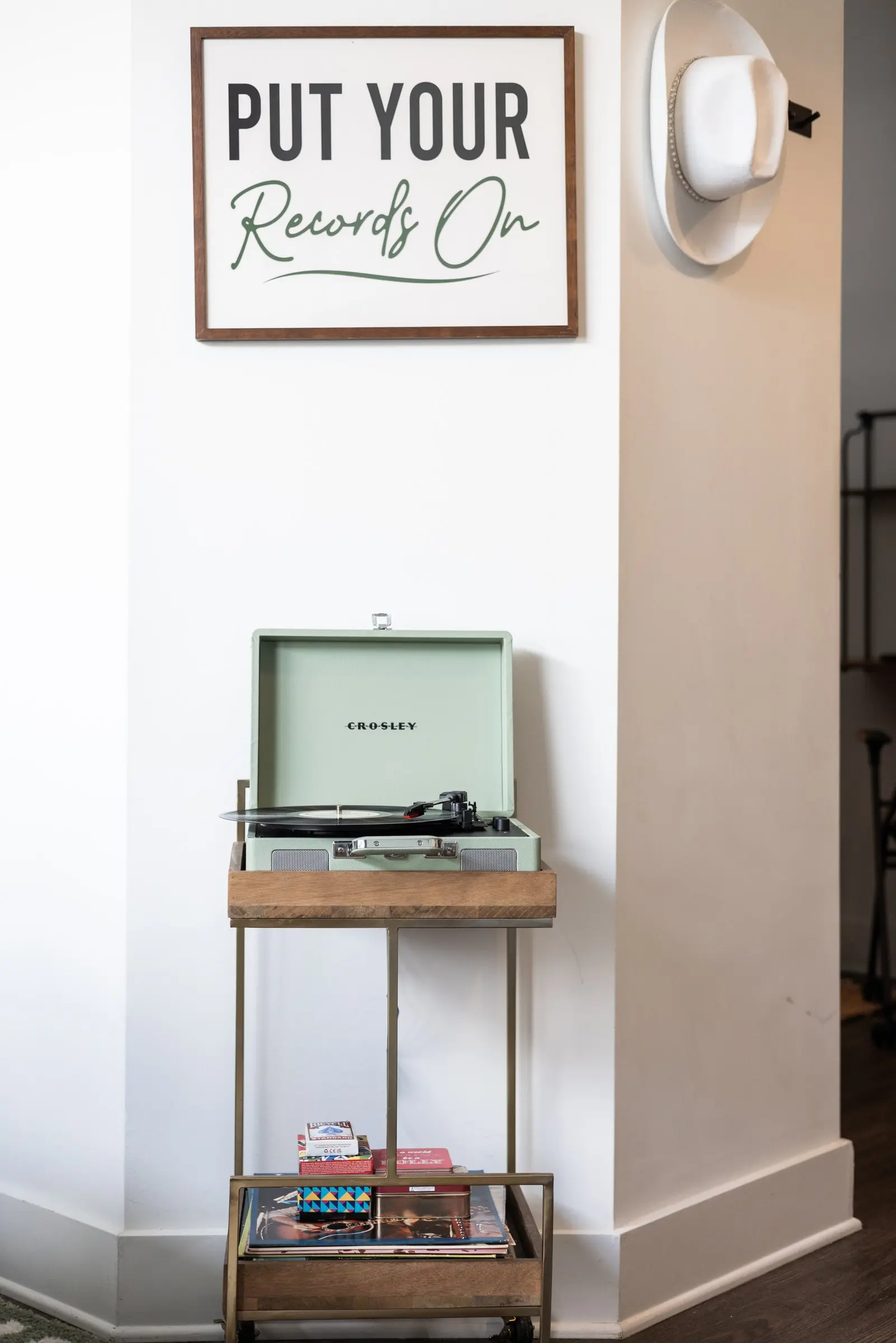 A Put Your Records On sign above a mint record player on a brass and wood stand